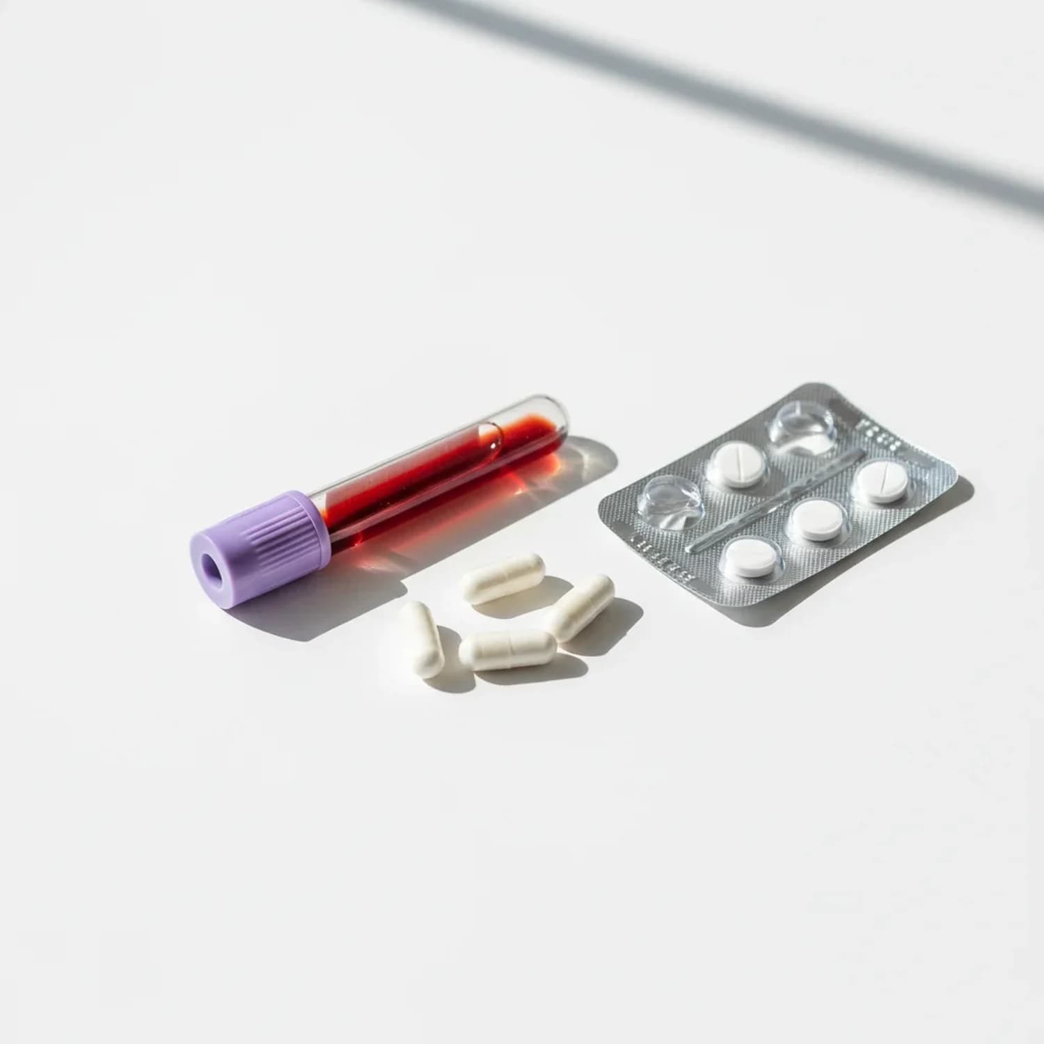 Test de alergia IgE Medicamentos: tubo de extracción de sangre junto a cápsulas y blíster de antibióticos — para evaluar sensibilización a penicilina y derivados.
