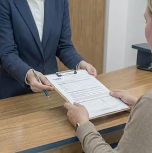 Recepción de Laboratorio Aclimu, paciente firmando la ficha de ingreso con el membrete ACLIMU